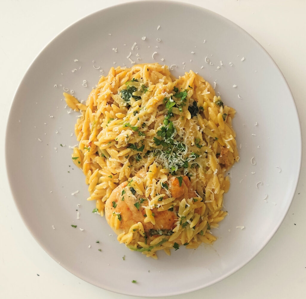 Kremowy makaron orzo z mięsem i pieczarkami, podany w jednej patelni, z dodatkiem szpinaku i suszonych pomidorów – szybki i sycący obiad rodzinny